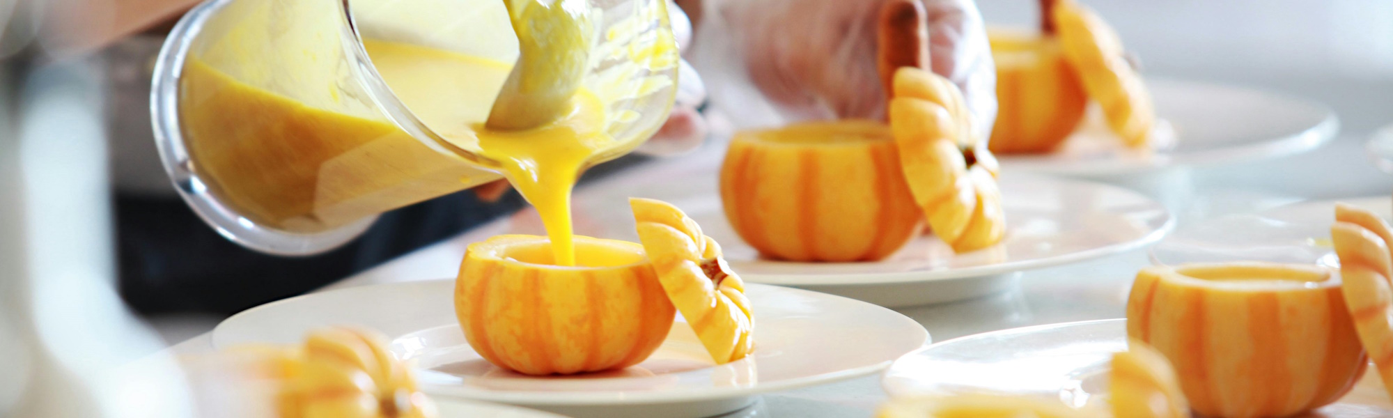 Chefs pouring soup into little pumpkins